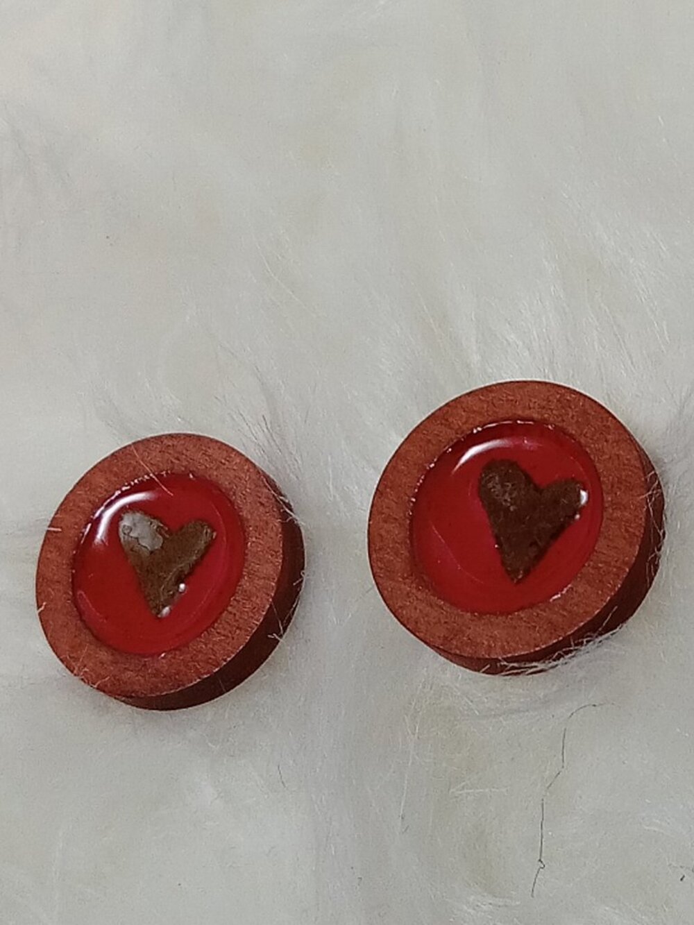 Handmade earrings on a wooden base with a piece of punched-out tree leaf